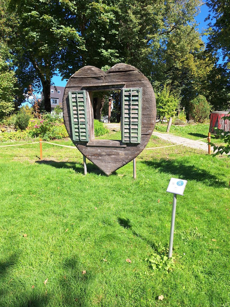 Vlevo Herz (Anne Knoll, dub, 1998), vpravo Bienenstock od Rumuna Dinu Campeanua (dub, 1998) pod věží farního kostela - Sochařský park Irdning - 18. 9. 2025 - Foto: Jiří Provazník